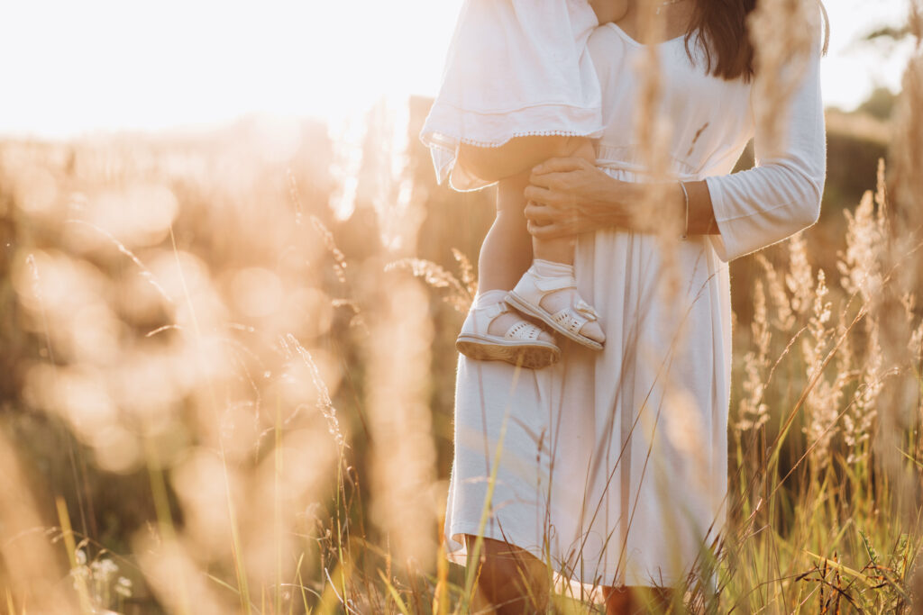 Image of mother holding daughter in a field of plants.