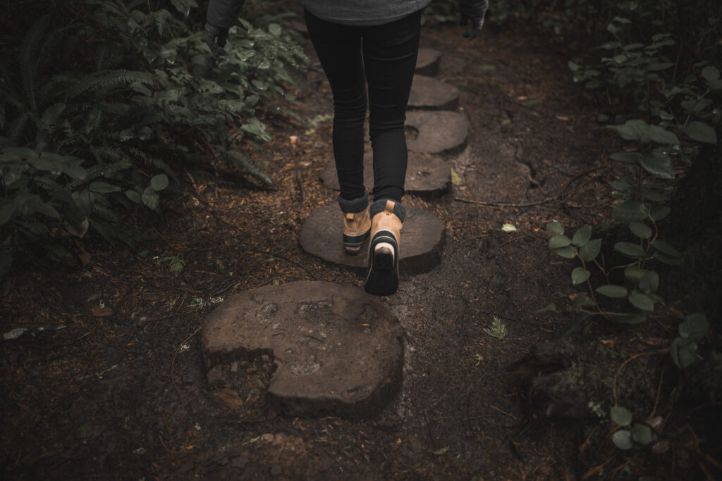 Cropped picture of a walking woman on wooden path.