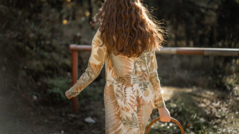 Woman in a nature field gathering mushrooms in a bast basket